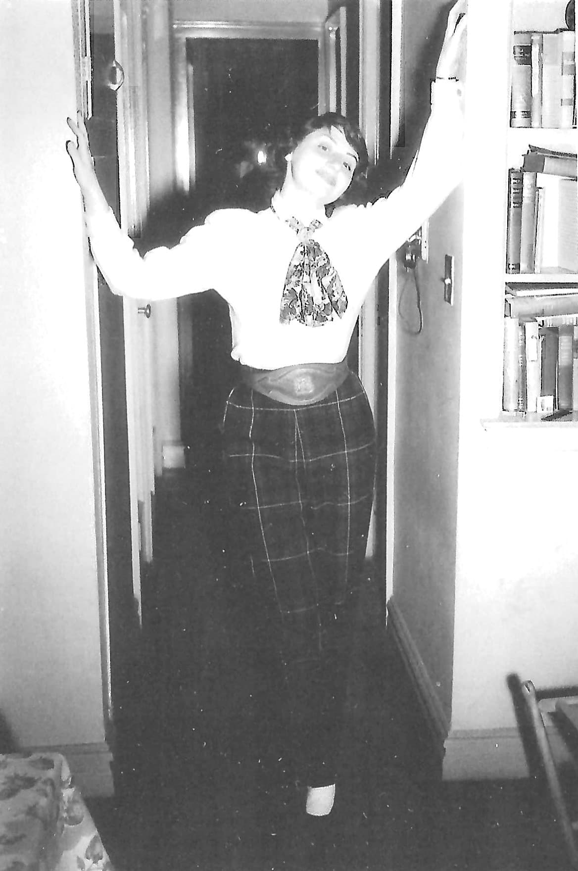 Rita Long smiling in a doorway with her arms raised